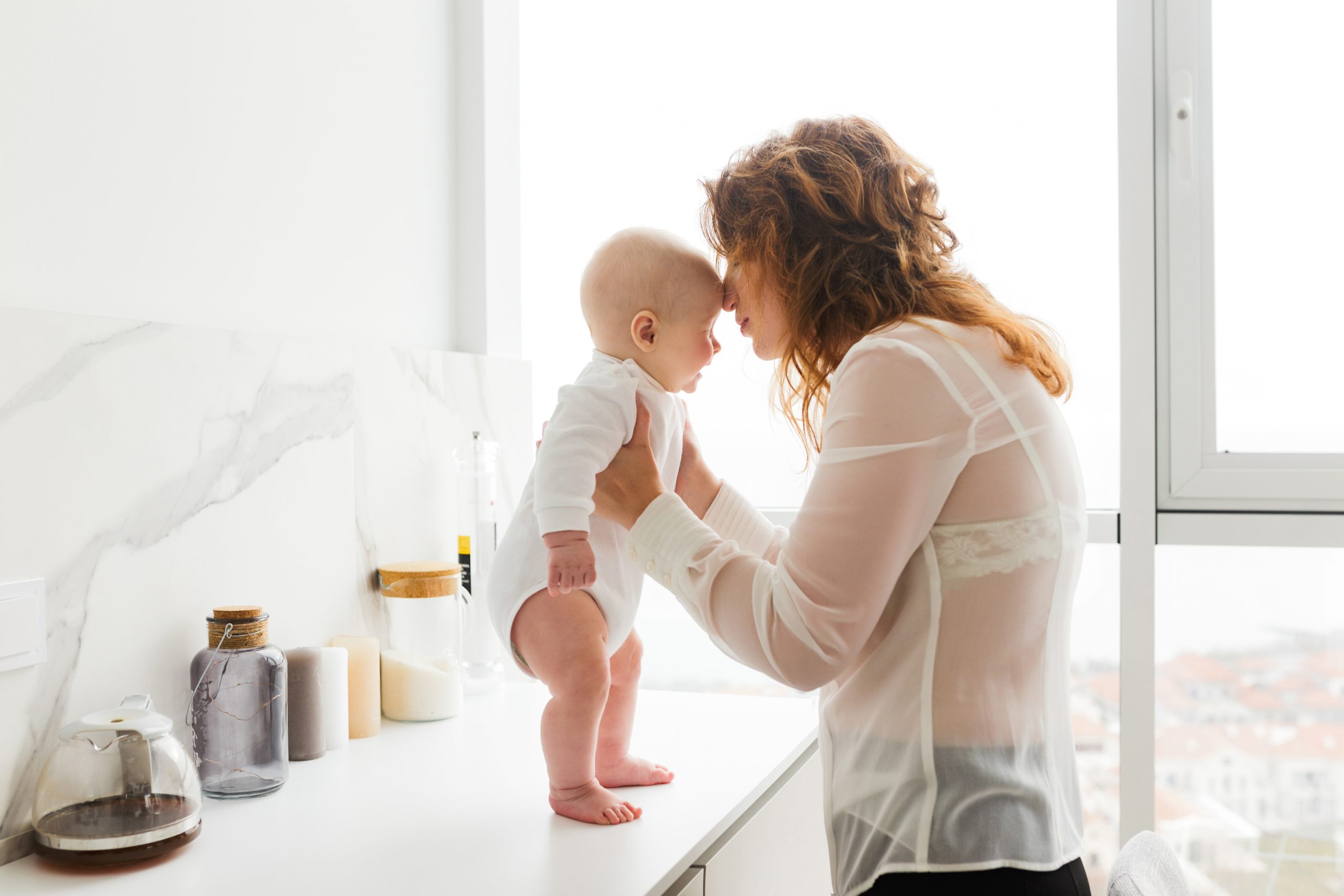 Beautiful woman standing and holding her pretty little baby in hands