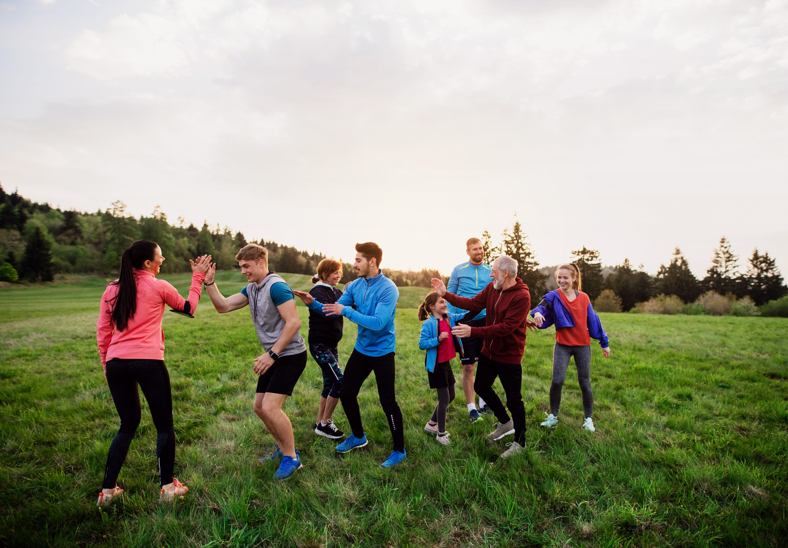 Large group of fit and active people resting after doing exercise in nature.